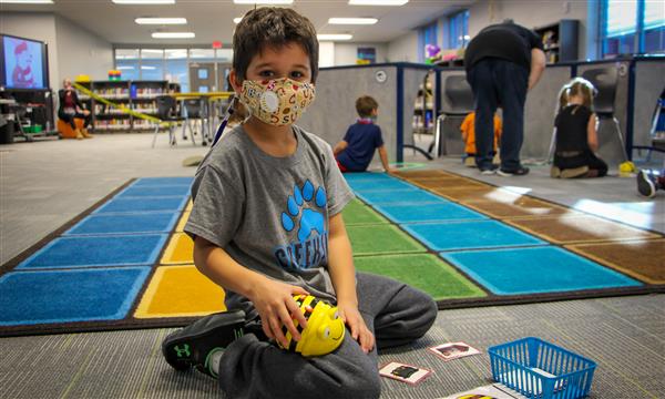 Boy smiles while holding BeeBot